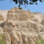 Ancient rock-cut caves carved into a rugged cliff.