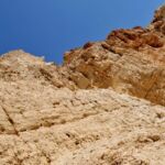 Rocky cliff face under clear blue sky.
