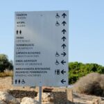 Directional signpost with distances in kilometers to various locations under a clear sky.