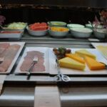 A deli counter with various sliced meats, cheeses, and condiments.