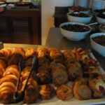Tray of assorted pastries with bowls of toppings in the background.