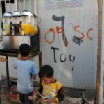 Children playing near a wall with graffiti in an urban setting.