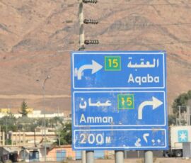 Road signs pointing to Aqaba and Amman in Jordan.