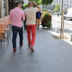 Two people walking down a city sidewalk on a sunny day.