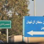 Two road signs in Arabic directing to different locations.