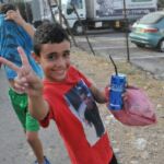 Smiling boy holding a toy gun outdoors.