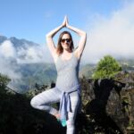 Woman practicing yoga outdoors on a sunny mountain day.