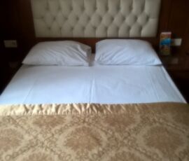 A neatly made bed with white pillows and a patterned bedspread.