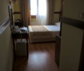 Cozy hotel room with bed and small desk near window.