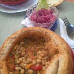 A bowl of soup served in an edible bread bowl with bread on the side.